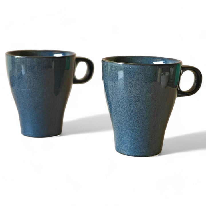 Display image of dark blue ceramic coffee mug with a glossy finish and ergonomic handle.