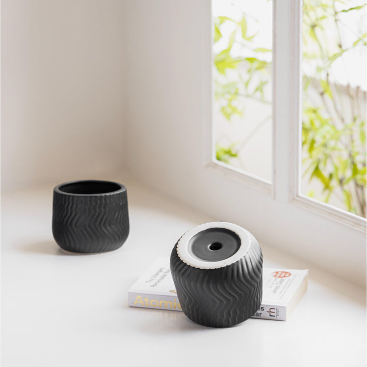 Display image of black ceramic planter with a wavy textured pattern and matte finish.