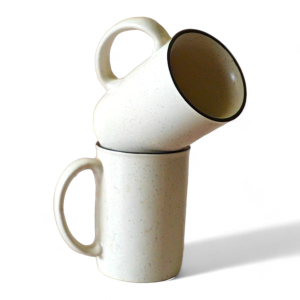 Display image of  speckled white ceramic mugs with a minimalist design and black rim.