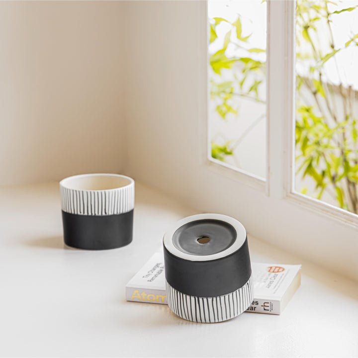 Display image of Black and white ceramic planter with vertical stripe detailing on the upper half and a smooth matte finish.