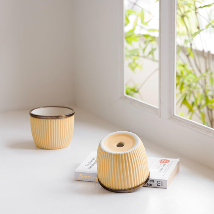 Handcrafted ceramic planter with a ribbed texture in a warm yellow tone and a brown rim, designed for indoor use.