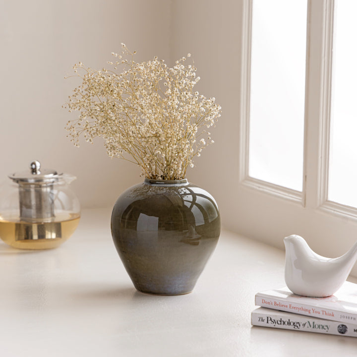 The Elegant Vase with dried flowers on a minimalistic tabletop next to books and a teapot.